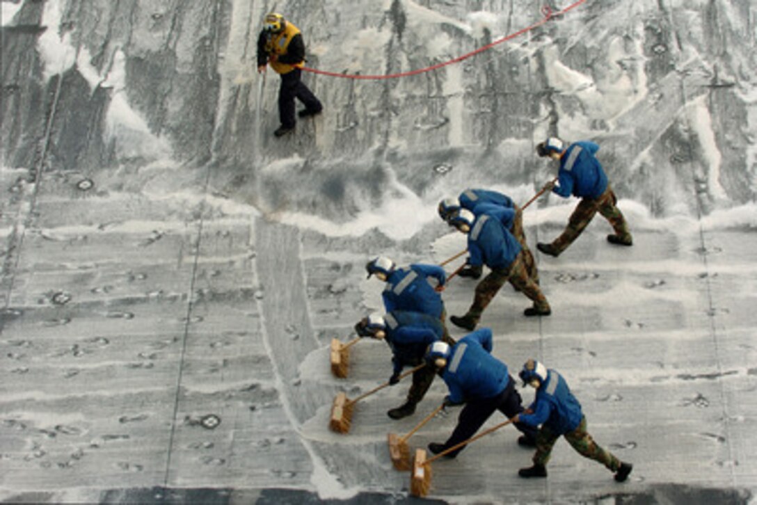 U.S. Navy aviation boatswain's mates scrub the flight deck of the amphibious assault ship USS Peleliu (LHA-5) after flight operations in the Pacific Ocean off the coast of Southern California on Dec. 14, 2005. The scrubbing removes the built-up dirt, hydraulic fluid and jet fuel from the deck. 