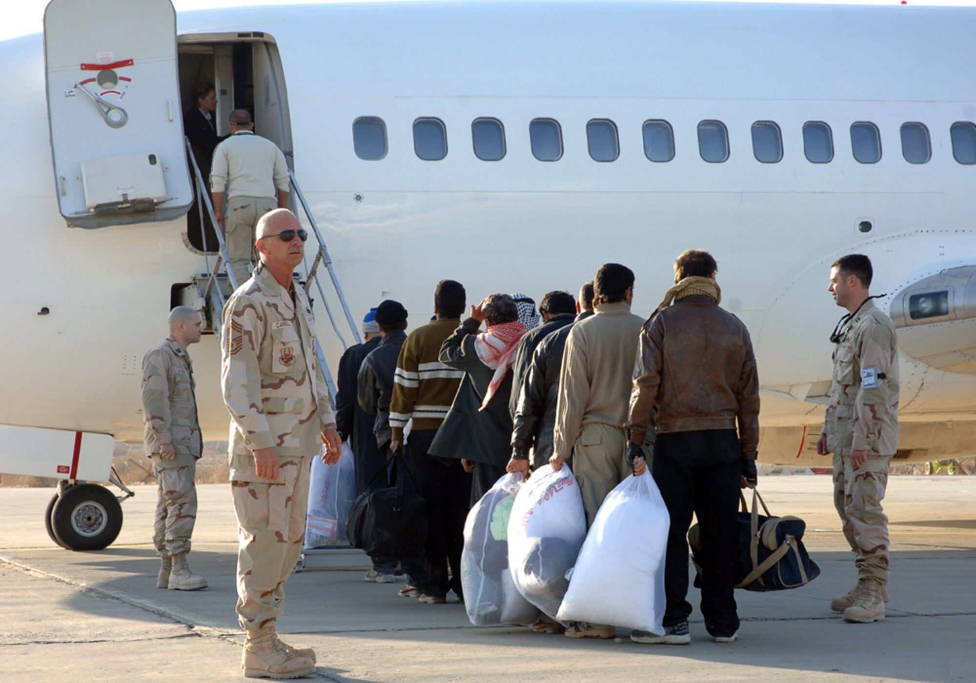 BAGHDAD, Iraq (AFPN) -- Chief Master Sgt. Ronald Carroll helps Iraqi election workers board a contract flight to polling sites.  He is with the 447th Expeditionary Logistics Readiness Squadron.  (U.S. Air Force photo by Master Sgt. Randy L. Mitchell)