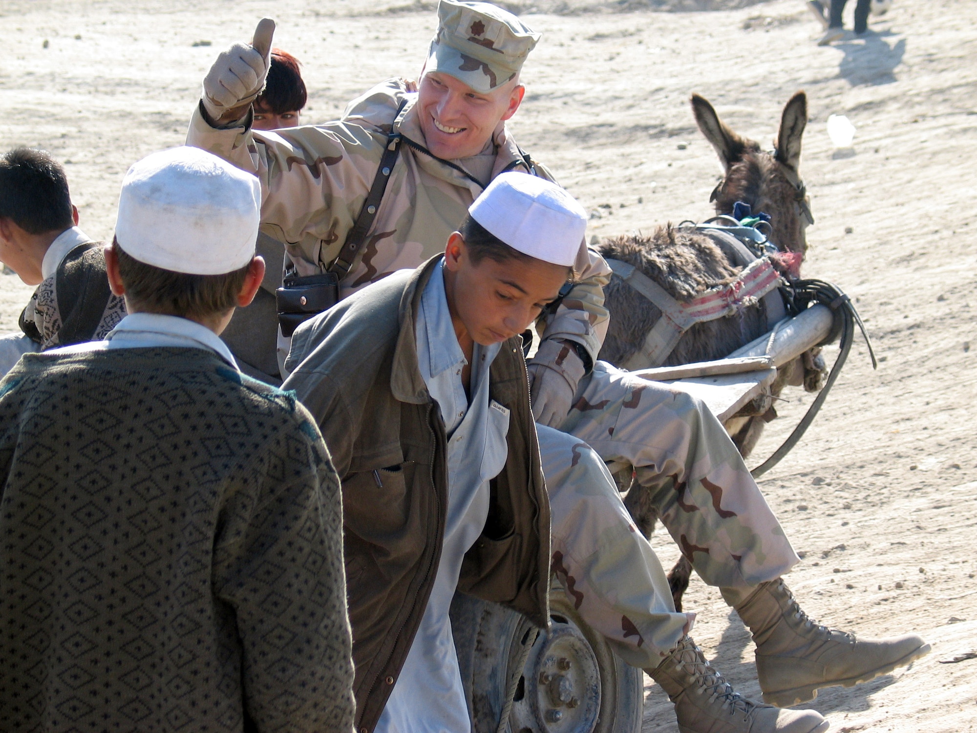 KABUL, Afghanistan (AFPN) -- Maj. Jeffrey Greenwood gets a donkey cart ride from his new friends at the Bagrami Village refugee camp here.  Major Greenwood visited the camp with other service members from nearby Camp Eggers to provide toys, snacks, clothing and other supplies to the villagers.  The Major is deployed from Vandenberg Air Force Base, Calif. (U.S. Air Force photo by Capt. Dave Huxsoll) 