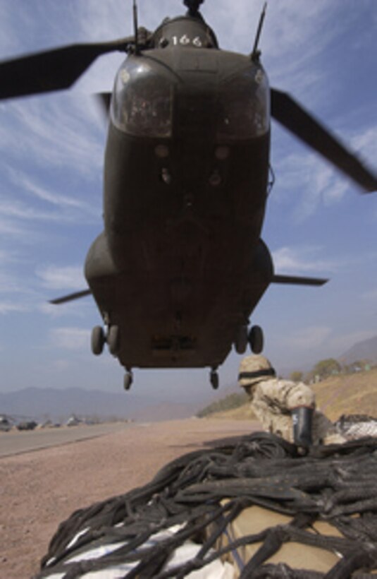 A soldier waits for hook-up as a U.S. Army CH-47D Chinook helicopter approaches a cargo net full of humanitarian relief supplies that will be sling loaded from Muzaffarabad, Pakistan, on Dec. 16, 2005. The Department of Defense is supporting the State Department by providing disaster relief supplies and services following the massive earthquake that struck Pakistan and parts of India and Afghanistan. 