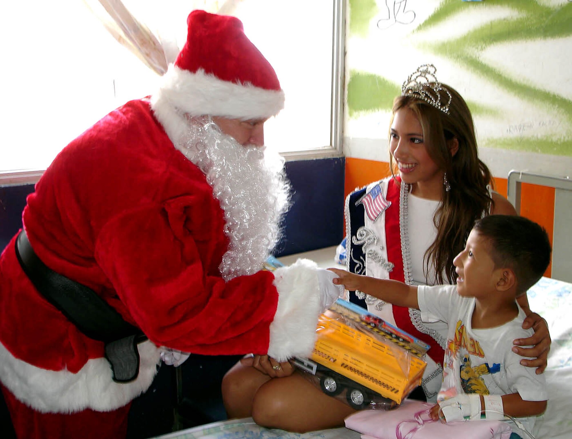 MANTA AIR BASE, Ecuador (AFPN) -- Santa Claus hands a toy to a child at a local hospital. Airmen will be giving 1,800 toys to children at schools, hospitals and community organizations for the holidays. (U.S. Air Force photo)