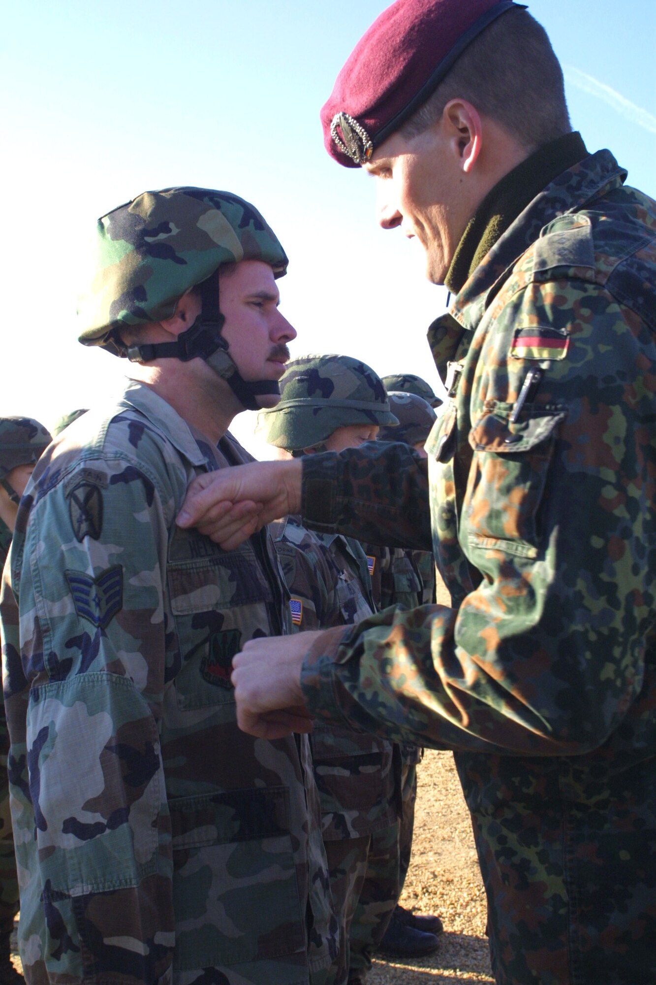 FORT BRAGG, N.C. (AFPN) -- Staff Sgt. Jefferson Helfrich receives his German jump wings from a German officer after Operation Toy Drop. Twelve Airmen joined more than 1,075 Soldiers in the charity jump. The toys are distributed to needy families at Pope Air Force Base, N.C., Fort Bragg, N.C., and in the local communities. Sergeant Helfrich is with the 18th Weather Squadron. (U.S. Air Force photo by Lisa Terry McKeown)