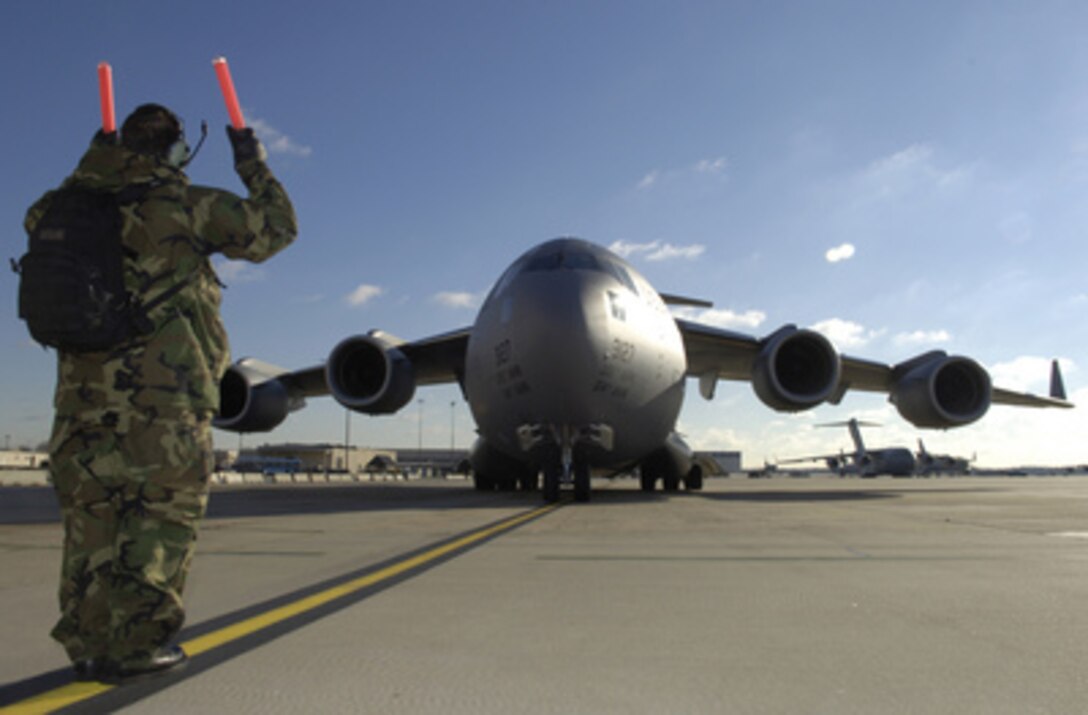 Air Force Airman 1st Class David Eskew directs the crew of a C-17 Globemaster III to a parking spot on the flight line at McGuire Air Force Base, N.J., on Dec. 16, 2005. The Globemaster was deployed as part of the 818th Contingency Response Group's mission to provide humanitarian assistance to Pakistan after a devastating earthquake hit the area on Oct. 8, 2005. Eskew is attached to the 305th Aircraft Maintenance Squadron at McGuire. 