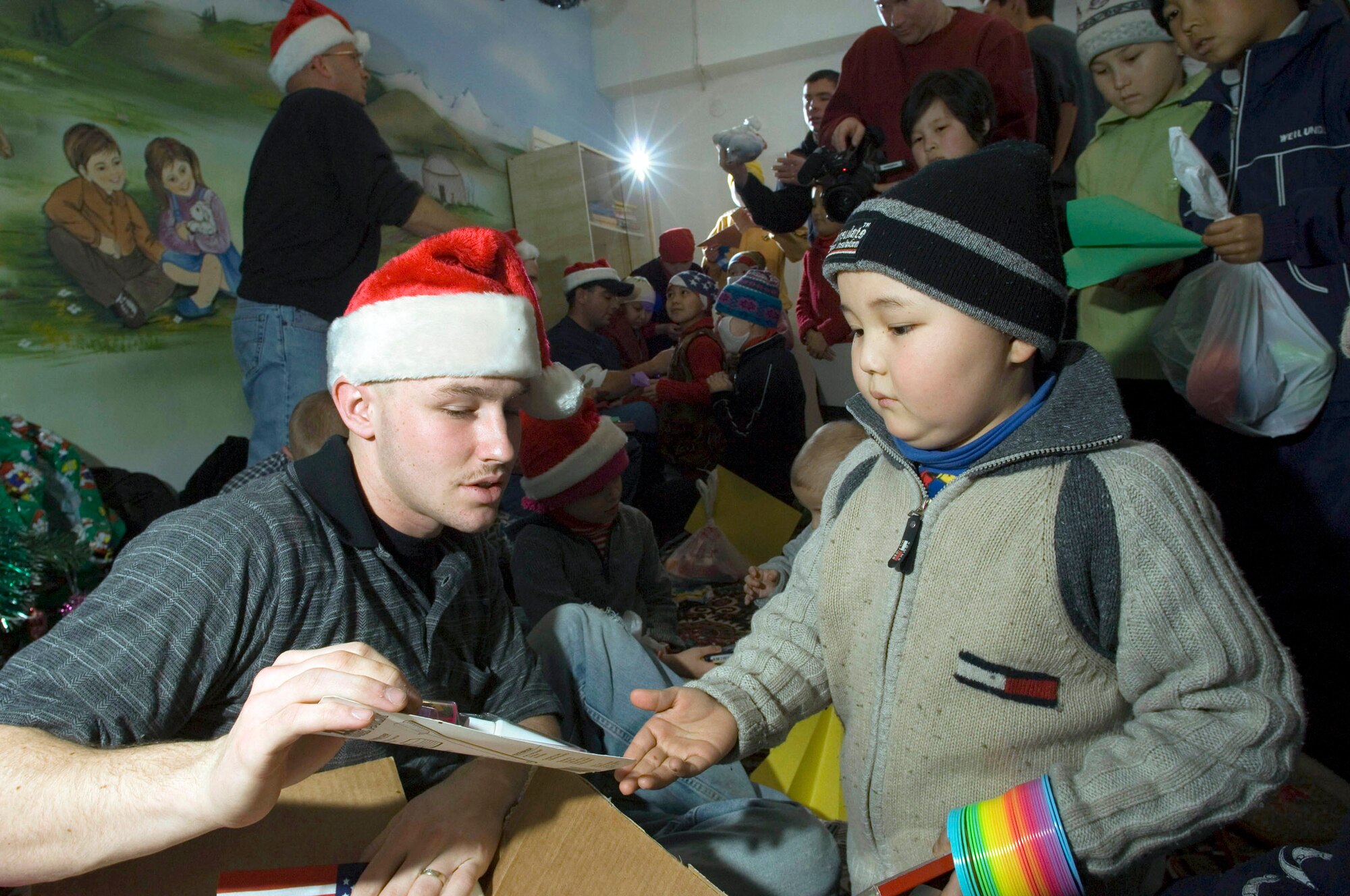 BISHKEK, Kyrgyzstan -- Airman 1st Class William Kretsch presents a gift to a young boy from the cancer ward in this hospital, compliments of the Manas Air Base Outreach Society. Airman Kretsch is an Air Force firefighter. (U.S. Air Force photo by Master Sgt. John E. Lasky) 