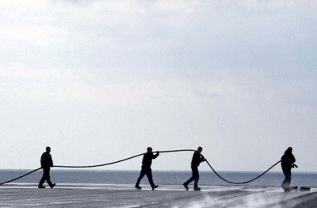 Sailors stretch out a fire hose across the flight deck of the aircraft carrier USS Ronald Reagan (CVN 76) as the ship operates in the Pacific Ocean on Dec. 16, 2005. 