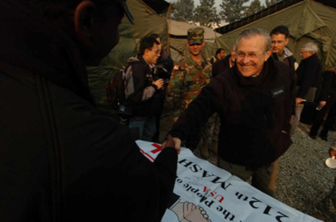 Secretary of Defense Donald H. Rumsfeld reaches out to shake a soldier's hand as he greets U.S. Army soldiers assigned to the 212th Mobile Army Surgical Hospital in Muzaffarabad, Pakistan, on Dec. 21, 2005. Rumsfeld is visiting the areas damaged by the Oct. 8, 2005, earthquake and meeting with the U.S. personnel working to aid the survivors. 