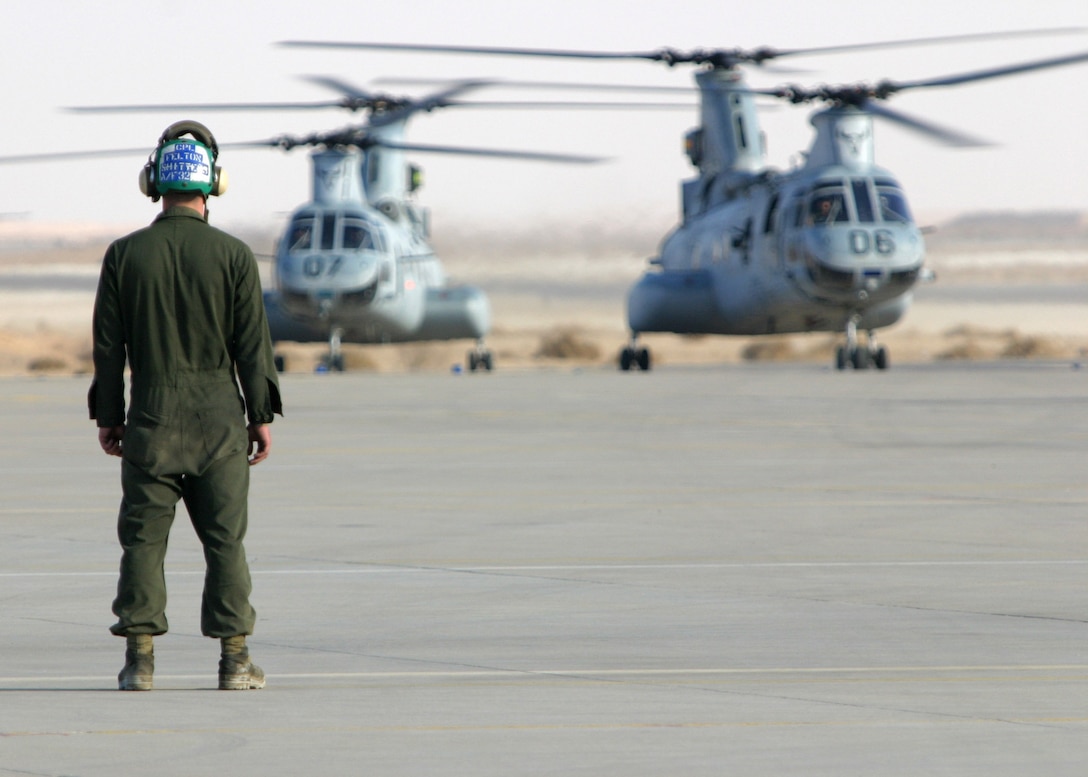 A Marine from Marine Medium Helicopter Squadron 261 (Reinforced), the aviation combat element of the 22nd Marine Expeditionary Unit (Special Operations Capable), watches as two CH-46E Sea Knight assault helicopters taxi toward him down the flight line aboard Al Asad Airfield, Iraq, Dec. 22, 2005.  The 22nd MEU (SOC) is currently deployed in Iraq's Al Anbar province in support of Operation Iraqi Freedom.