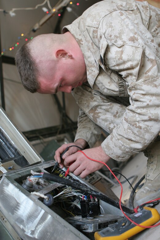 Pfc. Seth A. Eklund, refrigeration mechanic, Engineer's Platoon, 8th Communication Battalion, II Marine Expeditionary Force (Fwd), troubleshoots a military air conditioning unit here Dec. 21, 2005. The Engineer's Platoon has many junior Marines who hit the ground running upon arrival to Iraq.