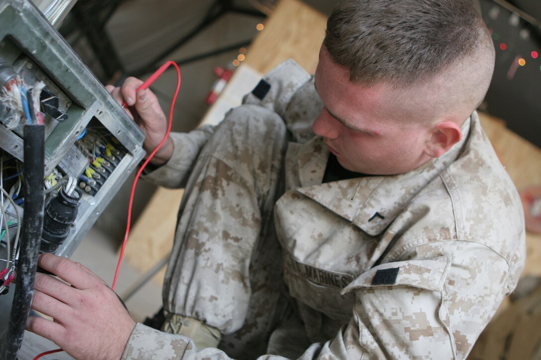 Pfc. Seth A. Eklund, refrigeration mechanic, Engineer's Platoon, 8th Communication Battalion, II Marine Expeditionary Force (Fwd), troubleshoots a military air conditioning unit here Dec. 21, 2005. Eklund, a native of Stryker, Ohio, and the Marines of the Engineer's Platoon make sure the unit's communication gear is fueled, cooled and ready for operation.