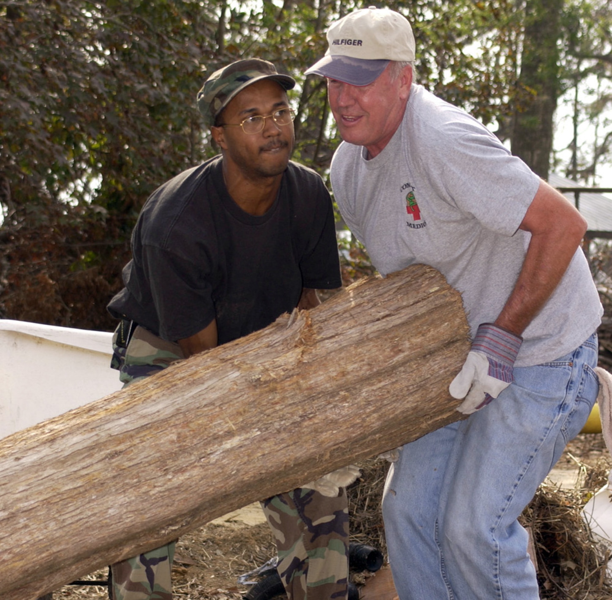 BILOXI, Miss. (AFPN) -- Staff Sgt. Frederick Braxton (left) and Col. Wade Jenkins move a cedar log while clearing storm debris at Camp Wilkes. The Boy Scouts' camp sustained extensive damage from Hurricane Katrina. Sergeant Braxton is with the 338th Training Squadron and Colonel Jenkins is with the 81st Medical Group. (U.S. Air Force photos by Kemberly Groue)