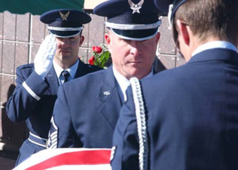 Captain Chris Silvia salutes the passing flag while Master Sgt. David McKay of the Team Kirtland Honor Guard and his pallbearer team move the casket to the gravesite. After placing the casket at the gravesite, the team will fold the flag before Captain Silvia presents it to the widow. (Air Force photo) 
