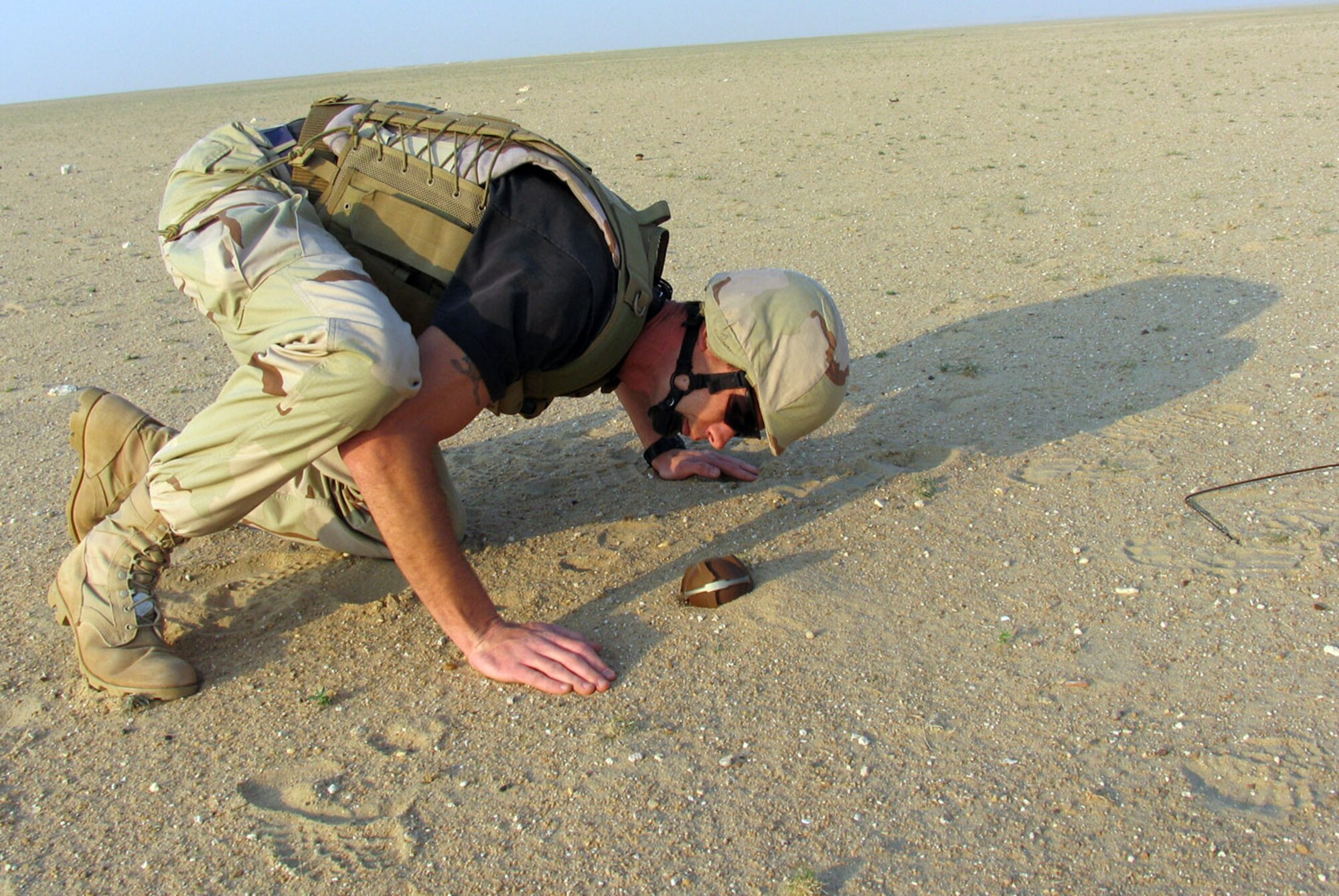 SOUTHWEST ASIA (AFPN) -- Staff Sgt. John Carroll inspects a bomblet found in the sand near here. The bomblet is of U.S. design and most likely dates back to the first Gulf War. Sergeant Carroll is a 386th Explosive Ordnance Disposal technician. (U.S. Air Force photo by Staff Sgt. Scott Campbell) 