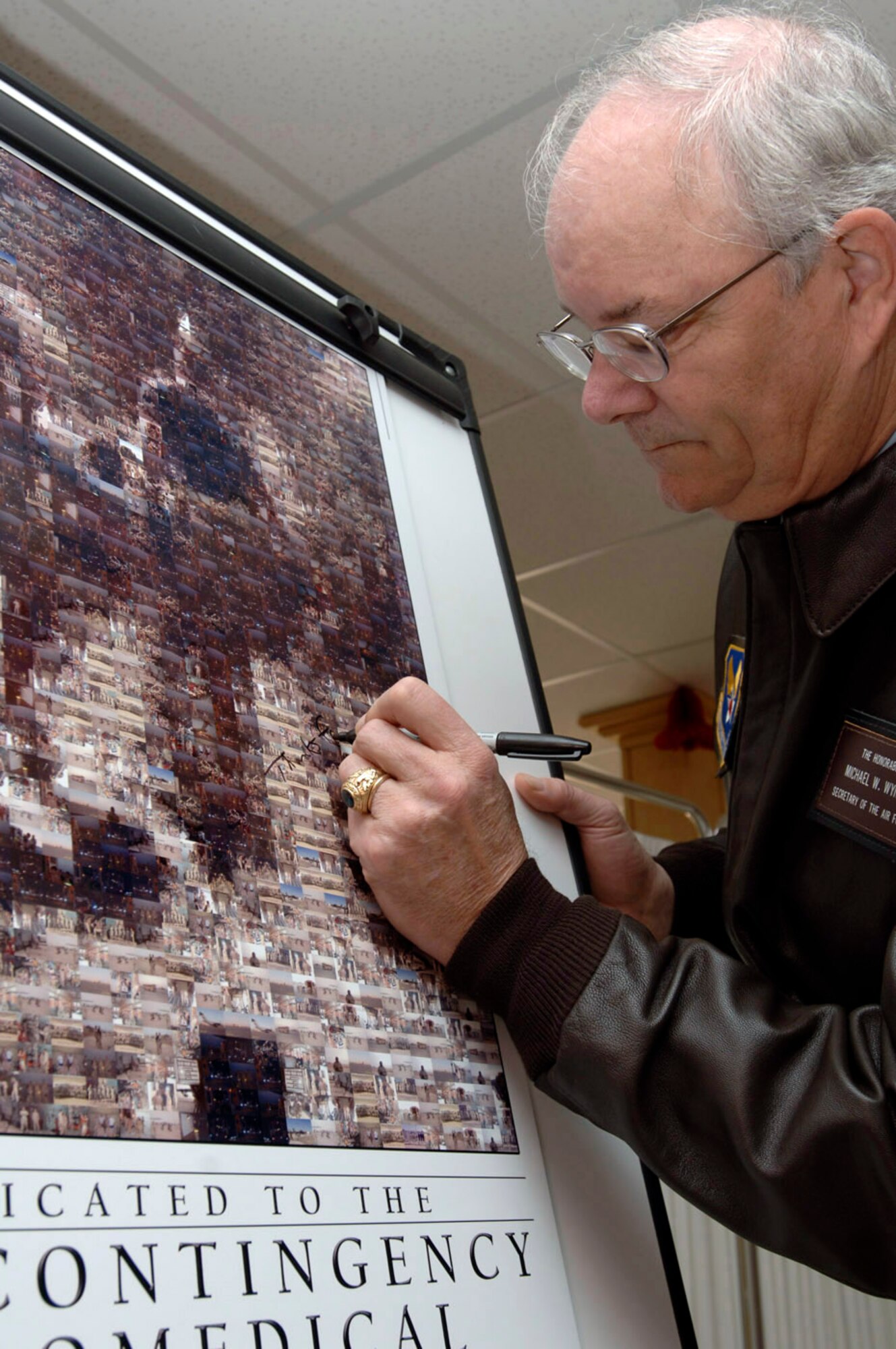 BALAD AIR BASE, Iraq (AFPN) -- Secretary of the Air Force Michael Wynne signs a poster at the Contingency Aeromedical Staging Facility after a ribbon cutting ceremony during a Balad visit. (U.S. Air Force photo by Airman 1st Class Chad Watkins)