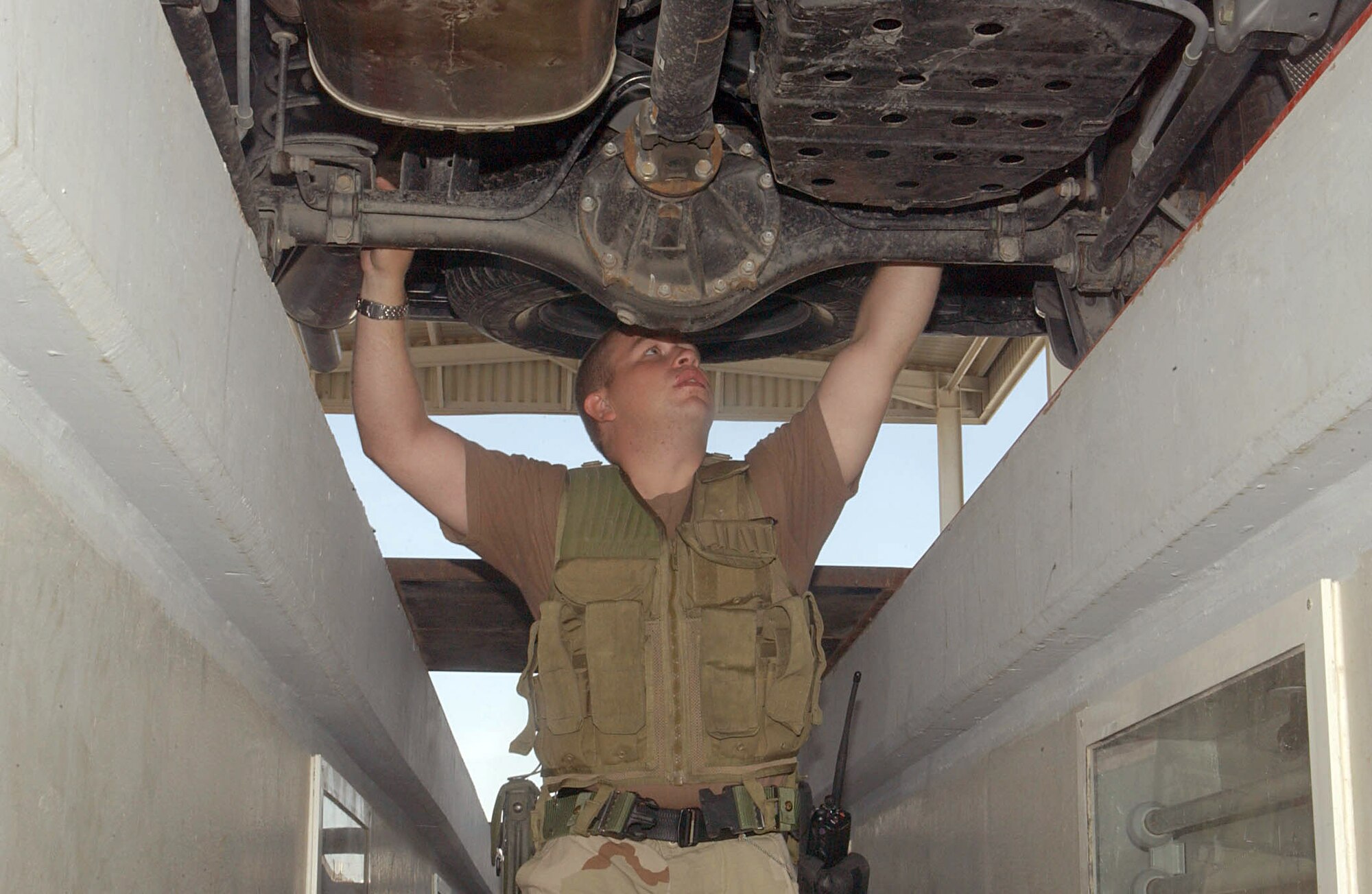 SOUTHWEST ASIA (AFPN) -- Senior Airman Nicholas Girton inspects a car's undercarriage at the vehicle search area at this desert air base on Christmas Eve.  Airman Girton and other members of the 380th Expeditionary Security Forces Squadron continued their efforts to keep the base members and assets secure this holiday season.  Airman Girton is deployed from the 15th Security Forces Squadron at Hickam Air Force Base, Hawaii. (U.S. Air Force photo by Tech. Sgt. Mike Hammond)