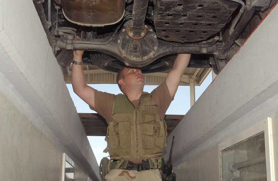 SOUTHWEST ASIA (AFPN) -- Senior Airman Nicholas Girton inspects a car's undercarriage at the vehicle search area at this desert air base on Christmas Eve.  Airman Girton and other members of the 380th Expeditionary Security Forces Squadron continued their efforts to keep the base members and assets secure this holiday season.  Airman Girton is deployed from the 15th Security Forces Squadron at Hickam Air Force Base, Hawaii. (U.S. Air Force photo by Tech. Sgt. Mike Hammond)