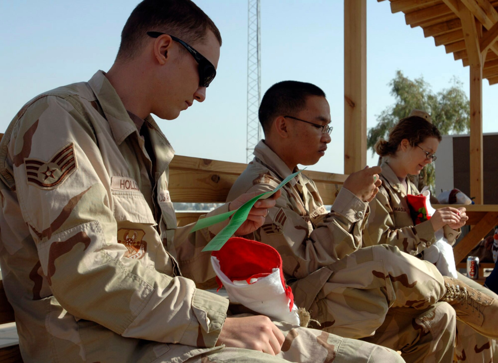 BALAD AIR BASE, Iraq (AFPN) -- (Left to right) Staff Sgt. Anthony Holloway, Senior Airman Class Rocky Tuvera and 2nd Lt. Shannon Maquire open stockings during the 332nd Expeditionary Communications Squadron Christmas party. (U.S. Air Force photo by Senior Airman Anthony Williams) 