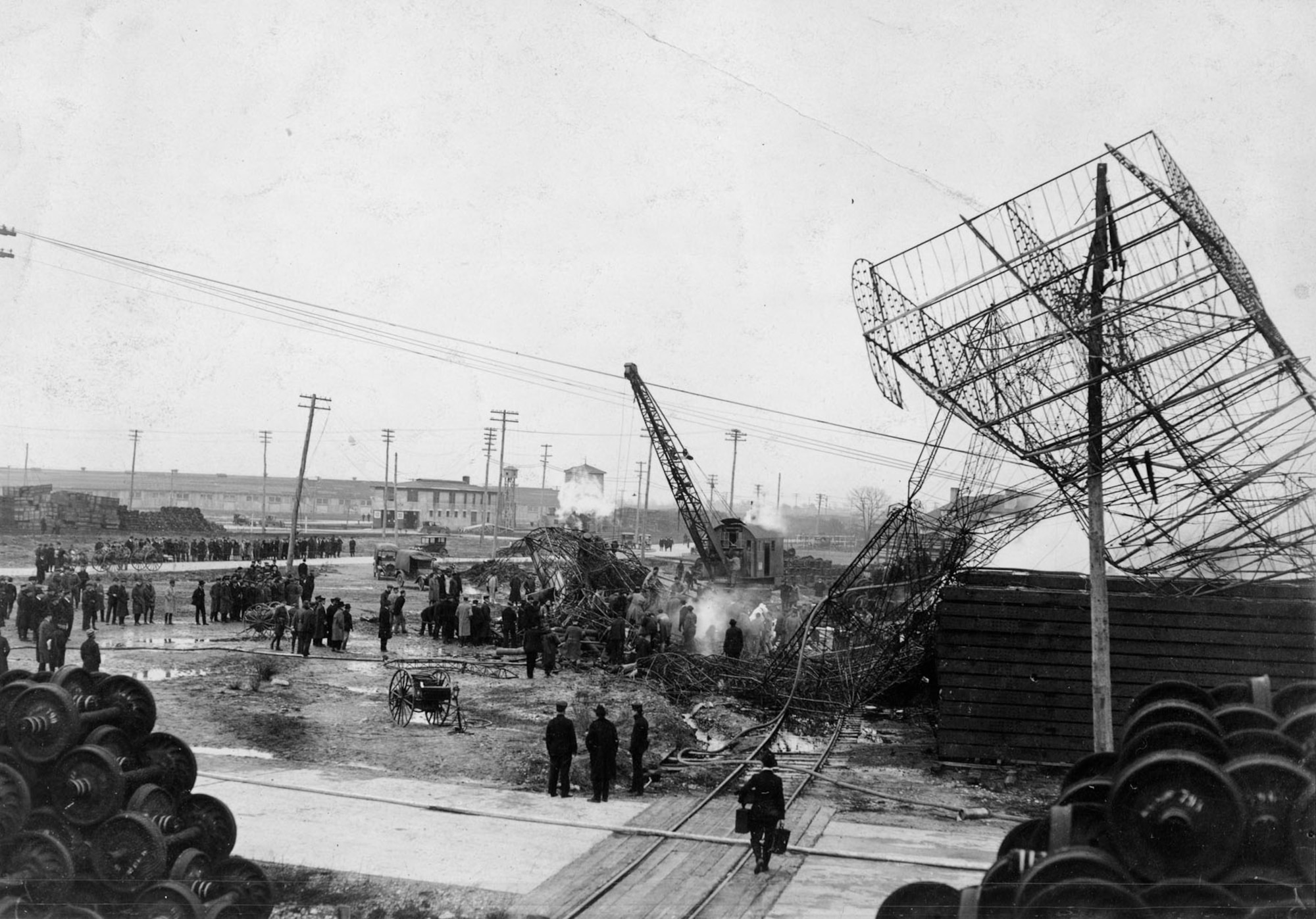 Spectators watch as a crane removes the twisted metal of the crashed Roma. Note how the steering assembly remained caught in a telephone pole on the right. (U.S. Air Force photo)