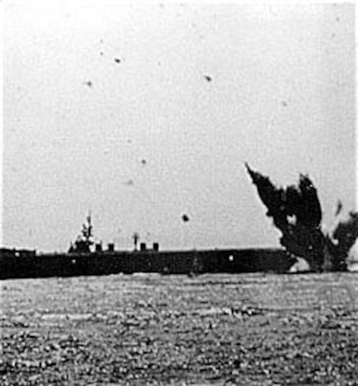 A kamikaze plane crashes just astern of a light carrier beneath a sky filled with antiaircraft bursts. (U.S. Air Force photo)