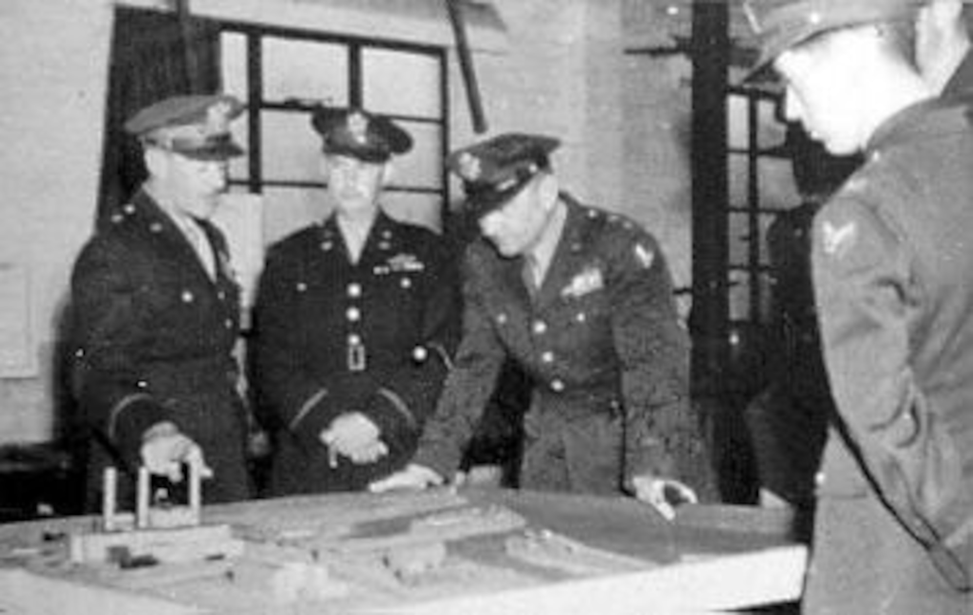Maj. Gen. Francis S. Brady, Commanding Officer of the B-26 unit that lost all 10 planes on the May 17, 1943, mission, "explains" to Maj. Gen. Ira C. Eaker why none returned to England. They are looking at the same model of the target as the crews in the next photograph. (U.S. Air Force photo)