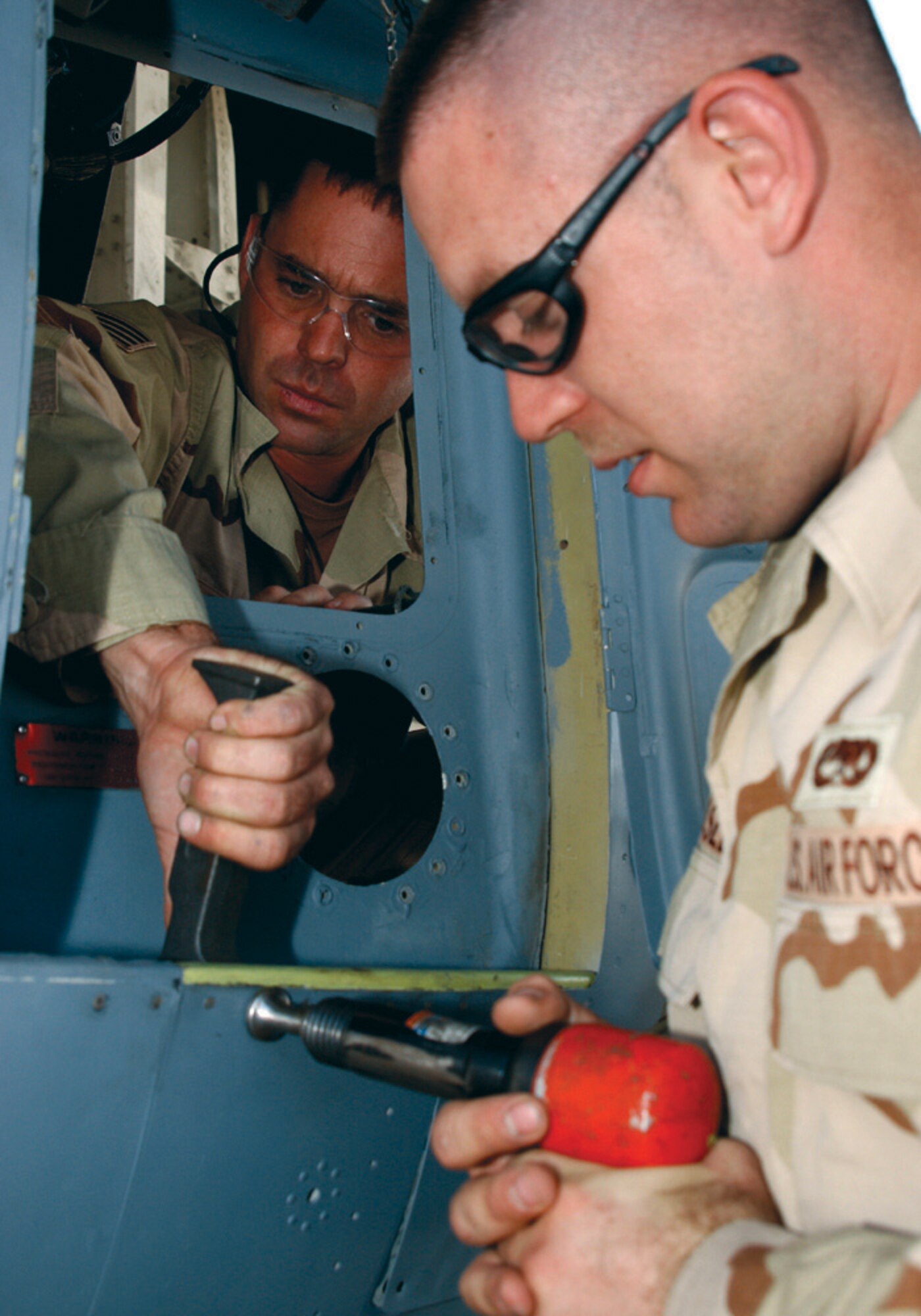 SOUTHWEST ASIA (AFPN) -- Staff Sgt. James Quick (left) and Airman 1st Class Jaime Easley help to repair the gear door of a damaged C-130 Hercules. The aircraft from Elmendorf Air Force Base, Alaska, is deployed to Manas Air Base, Kyrgyzstan. One of the aircraft's tires blew, causing gear door damage. The repair took about a month.  Both Airmen are structure repair technicians with the 379th Expeditionary Maintenance Squadron.  (U.S. Air Force photo by Tech. Sgt. Sarah Webb)                           