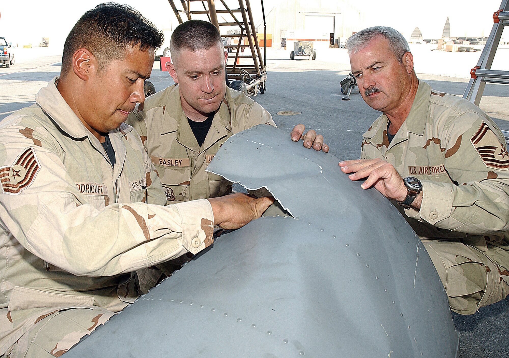 SOUTHWEST ASIA (AFPN) -- Tech. Sgt. Abel Rodriguez (left), Airman 1st Class Jaime Easley and Senior Master Sgt. Charles Liljestrand survey damaged sheet metal from a C-130 Hercules to determine whether it can be repaired. The repair team ordered parts for the aircraft from manufacturers while making some parts themselves.   They are all with the 379th Expeditionary Maintenance Squadron.  (U.S. Air Force photo by Airman 1st Class DeJuan Haley) 