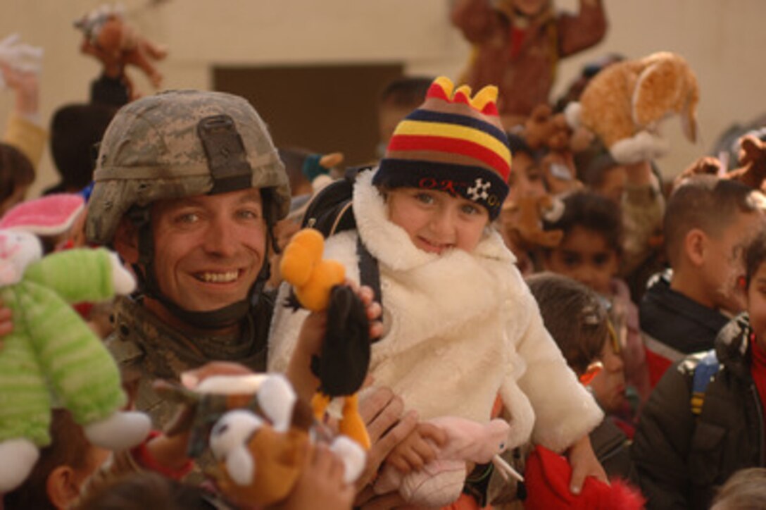 Army Staff Sgt. Richard Long holds up a little Iraqi girl with a new coat at the Dar Al Zando Kindergarten and Orphanage in Mosul, Iraq, on Dec. 22, 2005. Soldiers from several units brought donated clothing, toys and school supplies to give to the children. Long is attached to Alpha Troop, 4th Battalion, 14th Regiment, Mortar Platoon. 