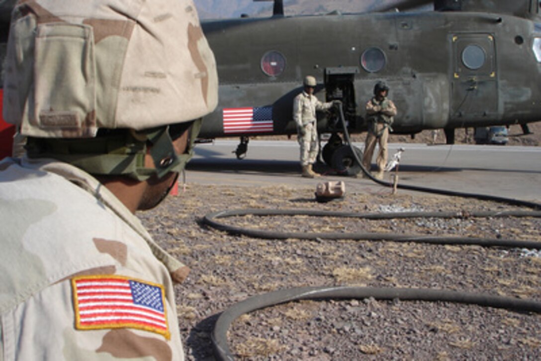 U.S. Army Sgt. George Bowe (left) keeps an eye on the crew chief of a CH-47 Chinook helicopter during refueling in Muzaffarabad, Pakistan, on Dec. 25, 2005. The Chinook and its crew are airlifting relief supplies to remote locations in Pakistan. The Department of Defense is supporting the State Department by providing disaster relief supplies and services following the massive earthquake that struck Pakistan and parts of India and Afghanistan. 