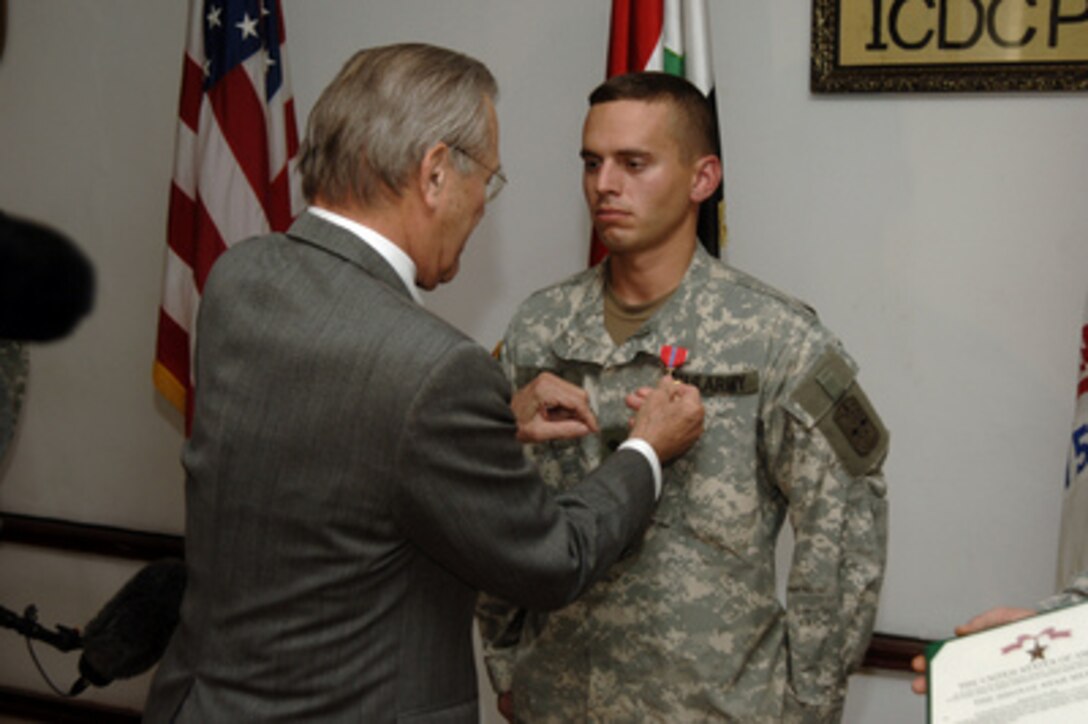 Secretary of Defense Donald H. Rumsfeld awards a Bronze Star to Army Spc. Lucas Crowe at Forward Operating Base Courage in Mosul, Iraq, on Dec. 24, 2005. Crowe took action that saved a two-year old Iraqi boy's life after he was found in his family's flooded basement in Mosul on Election Day, Dec. 15, 2005. Crowe performed cardiopulmonary resuscitation on the boy and comforted him until be could receive proper medical attention. Rumsfeld has been visiting in the troops in Pakistan, Afghanistan, Jordan and Iraq thanking them for their service and wishing them a happy holiday season. Crowe is attached to the 2-1st Infantry Regiment, Multi-National Force Northwest. 