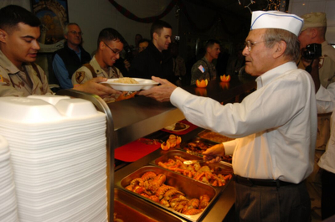 Secretary of Defense Donald H. Rumsfeld serves Christmas Eve dinner to the troops assigned to Forward Operating Base Courage in Mosul, Iraq, on Dec. 24, 2005. Rumsfeld has been visiting in the troops in Pakistan, Afghanistan, Jordan and Iraq thanking them for their service and wishing them a happy holiday season. 