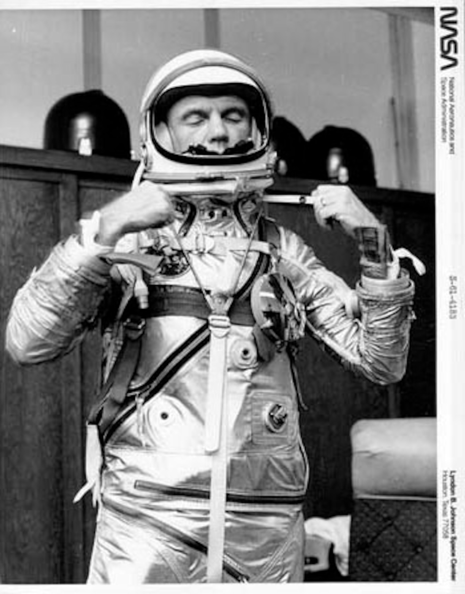 This NASA photo S-61-4183 from the Mercury program shows John Glenn adjusting his spacesuit.