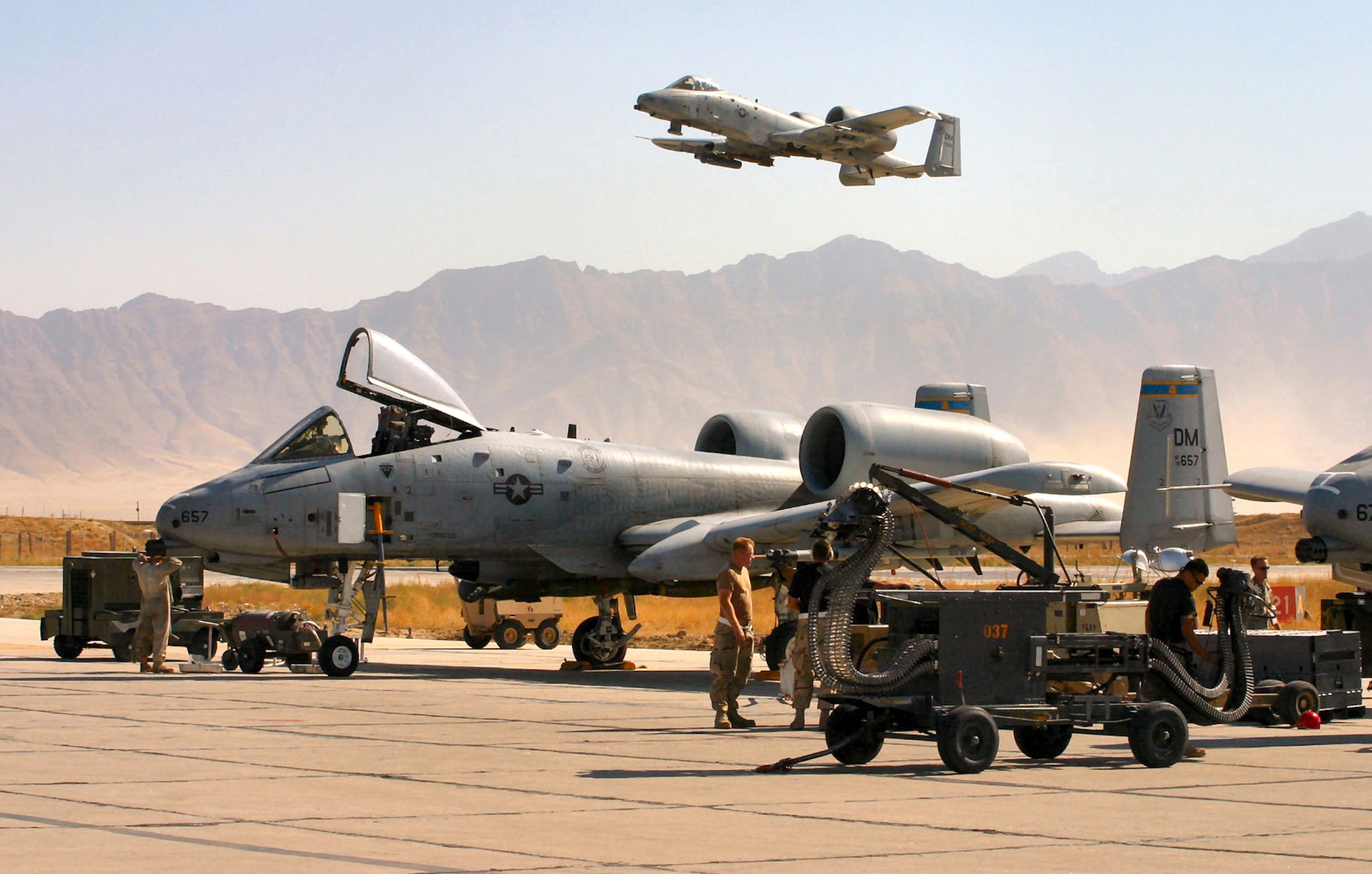BAGRAM AIR BASE, Afghanistan (AFPN) -- An A-10 Thunderbolt II takes off on a combat mission as A-10 crew chiefs, weapons loaders and an avionics specialist ready others for another mission. Since Sept. 15, A-10s here have flown more than 1,700 combat sorties, totaling more than 6,000 combat hours in support of Operation Enduring Freedom. The A-10 was the first Air Force aircraft specially designed for close air support of ground forces. (U.S. Air Force photo by Chief Master Sgt. David L. Stuppy) 
