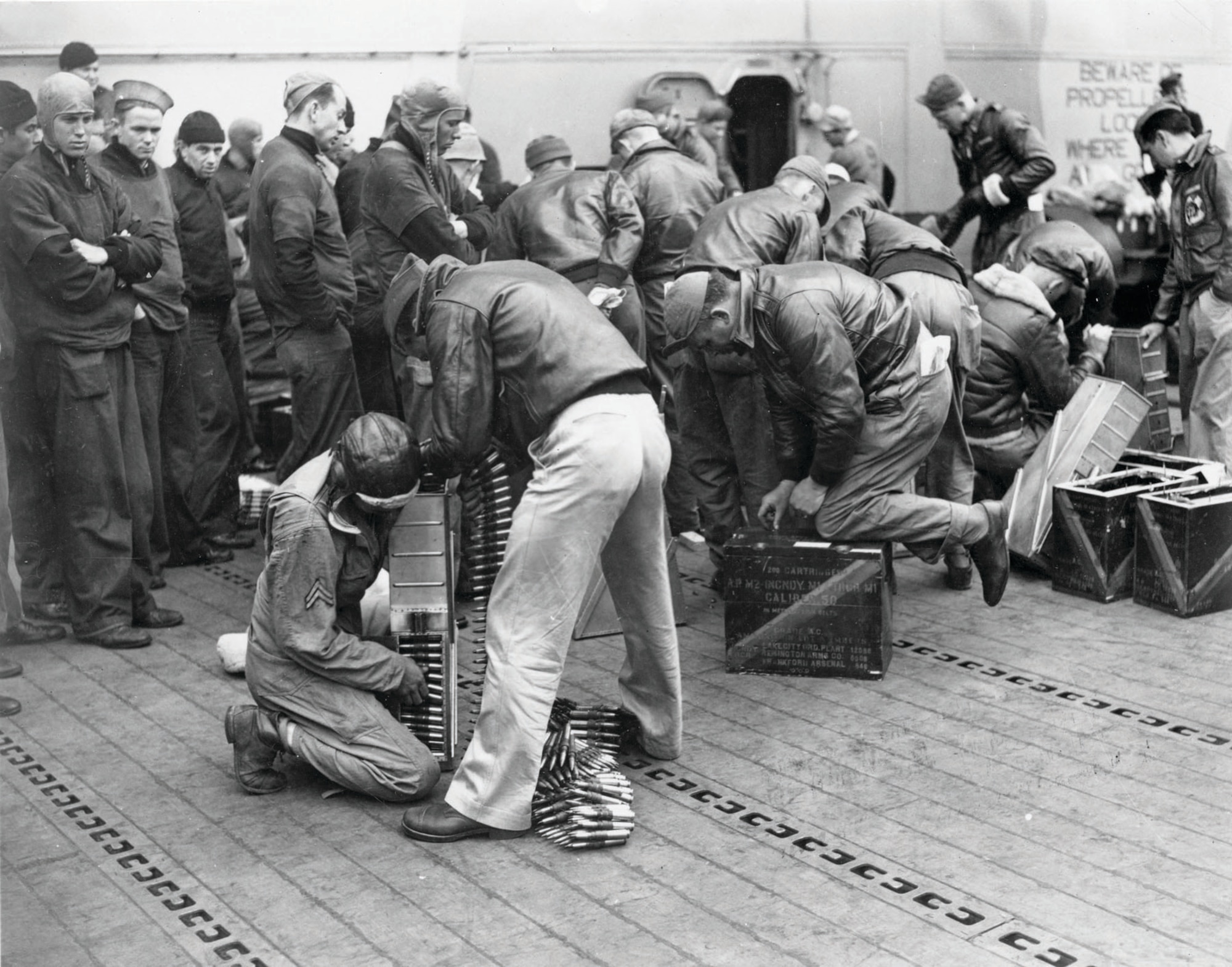USAAF personnel load .50-cal. ammunition into ammo trays prior to takeoff from the Hornet as Navy personnel watch. (U.S. Air Force photo)