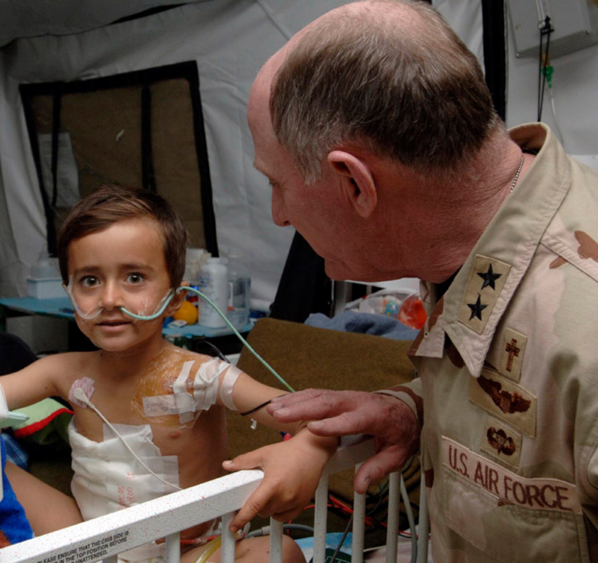 BALAD AIR BASE, Iraq (AFPN) -- Chaplain (Maj. Gen.) Charles Baldwin, Air Force Chaplain Service chief, visits an Iraqi child being treated at the Air Force theater hospital for injures from an insurgent mortar attack. (U.S. Air Force photo by Airman 1st Class Chad Watkins)
