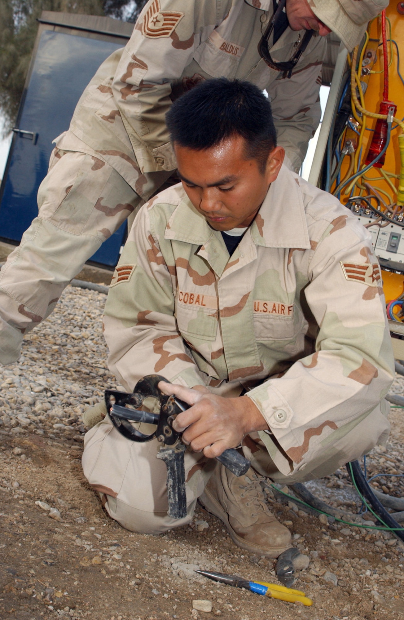 ALI BASE, Iraq (AFPN) -- Heavy rains on Christmas Day seeped into and shorted out wiring that served half of the 407th Air Expeditionary Group headquarters building. Airmen from the 407th Expeditionary Civil Engineering Squadron's electric shop dug a 150-foot trench and ran fresh wire. Here, Senior Airman Albert Escobal strips sheathing from the breaker box end of the wire before attaching it to a terminals. (U.S. Air Force photo by Tech. Sgt. Paul Dean)