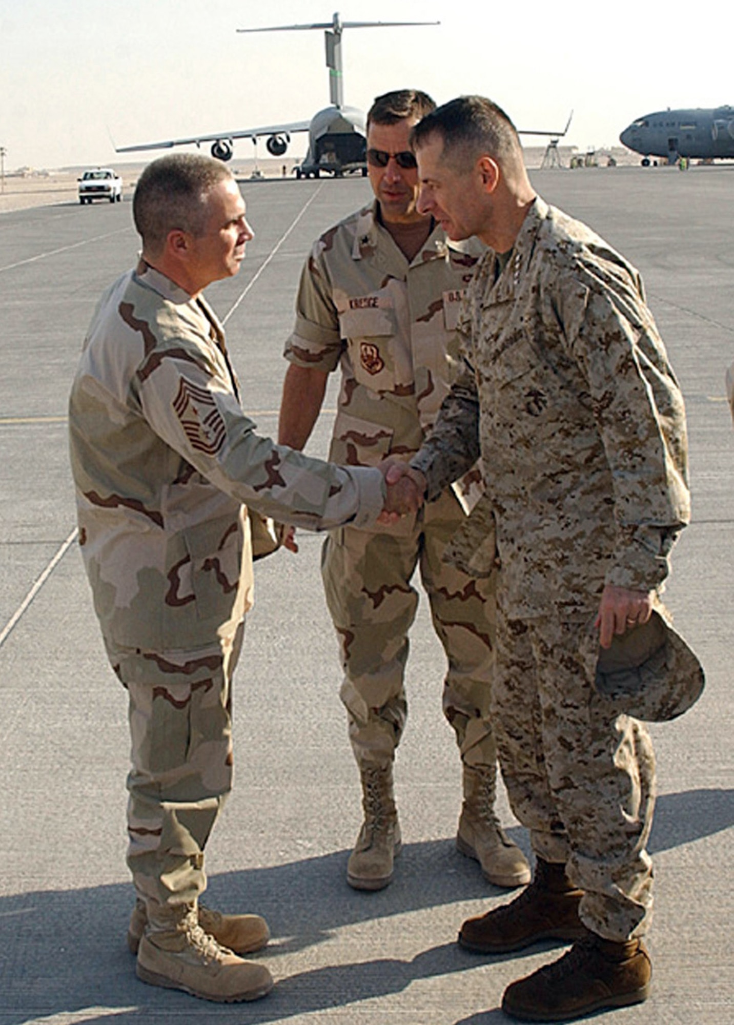 SOUTHWEST ASIA (AFPN) -- Marine Corps Gen. Peter Pace, chairman of the Joint Chiefs of Staff (right), gets a welcome to Southwest Asia from 379th Air Expeditionary Wing Command Chief Master Sgt. Dwayne Hopkins (left) and wing commander Brig. Gen. Stanley Kresge. General Pace visited this desert base Dec. 28. (U.S. Air Force photo by Airman 1st Class De-Juan Haley)