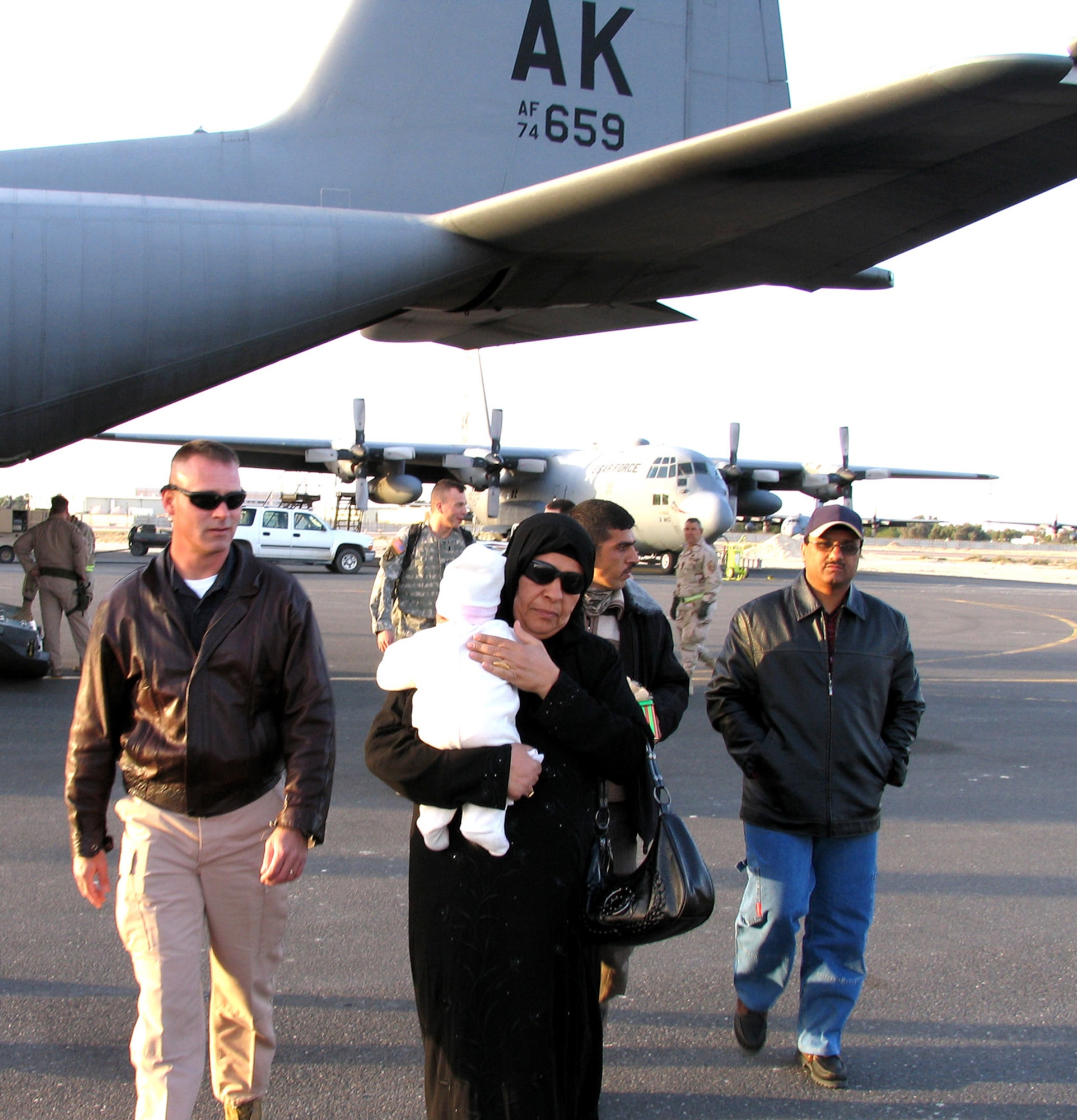 SOUTHWEST ASIA (AFPN) -- Baby Noor's grandmother and father take the infant, who has spina bifeda, from a 386th Air Expeditionary Wing C-130 Hercules to awaiting transportation. Officials from the U.S. Embassy in Kuwait met the family and escorted them to a civilian airport, from where the Iraqi family will continue their journey to the United States. (U.S. Air Force photo by Tech. Sgt. Mark Getsy)