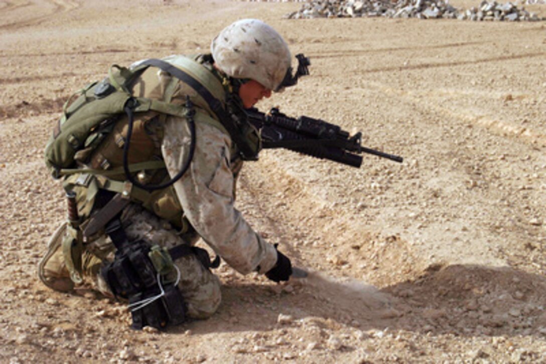 Marine Cpl. Jarret Bulskil of Kilo Company, 3rd Battalion, 1st Marine Regiment, uses a K-Bar bayonet to search the ground for any mines or other ordnance that may be shallowly buried during a sweeping patrol with Iraqi soldiers through Haditha, Iraq, on Dec. 21, 2005. 