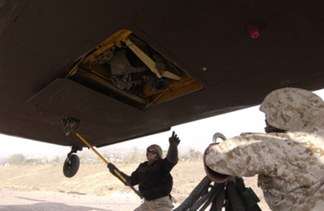 A member of the sling load crew discharges the static electricity from the CH-47D Chinook helicopter hovering over his head as another waits to attach the cargo net at Muzaffarabad, Pakistan, on Dec. 29, 2005. The Department of Defense is supporting the State Department by providing disaster relief supplies and services following the massive earthquake that struck Pakistan and parts of India and Afghanistan. 