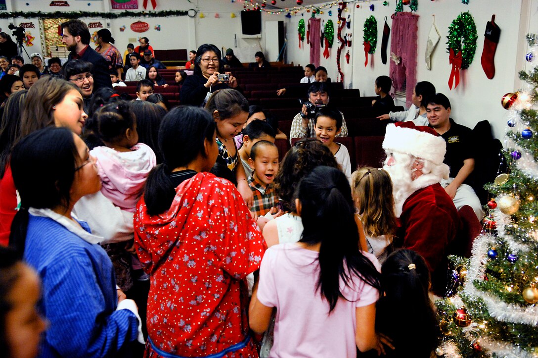 Children from the village of Kiana, Alaska gather around Santa as he prepares to distribute toys. This is the first time members of D Company (-) Anti-Terrorism Battalion, 4th Marine Division members assigned to Elmendorf Air Force Base, Alaska personally delivered toys to this region.