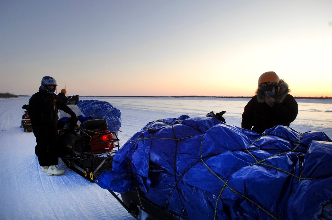 D Company (-) Anti-Terrorism Battalion, 4th Marine Division members assigned to Elmendorf Air Force Base, Alaska, and their guide Brad Reich, Mayor of Kiana, Alaska secure luggage before traveling by snow machine to deliver toys from the Toys for Tots program Dec. 16. This is the first time in the past 15 years that the Marines have personally delivered toys to the Kotzebue region.