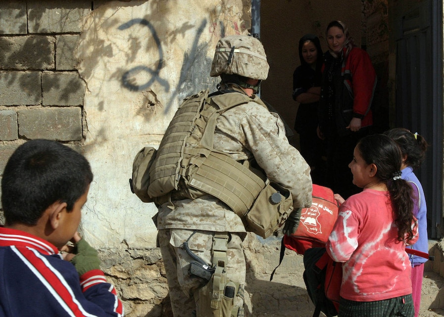 A Marine from Bravo Co., Battalion Landing Team 1st Bn., 2nd Marines gives local Iraqi children bags filled with school supplies in Hit, Iraq in an effort to engender goodwill between the Iraqi people and coalition forces, Dec. 30, 2005.  BLT 1/2 is the ground combat element of the 22nd Marine Expeditionary Unit (Special Operations Capable), which is in Iraq conducting counterinsurgency operations in Iraq's Al Anbar province with the 2nd Marine Division.