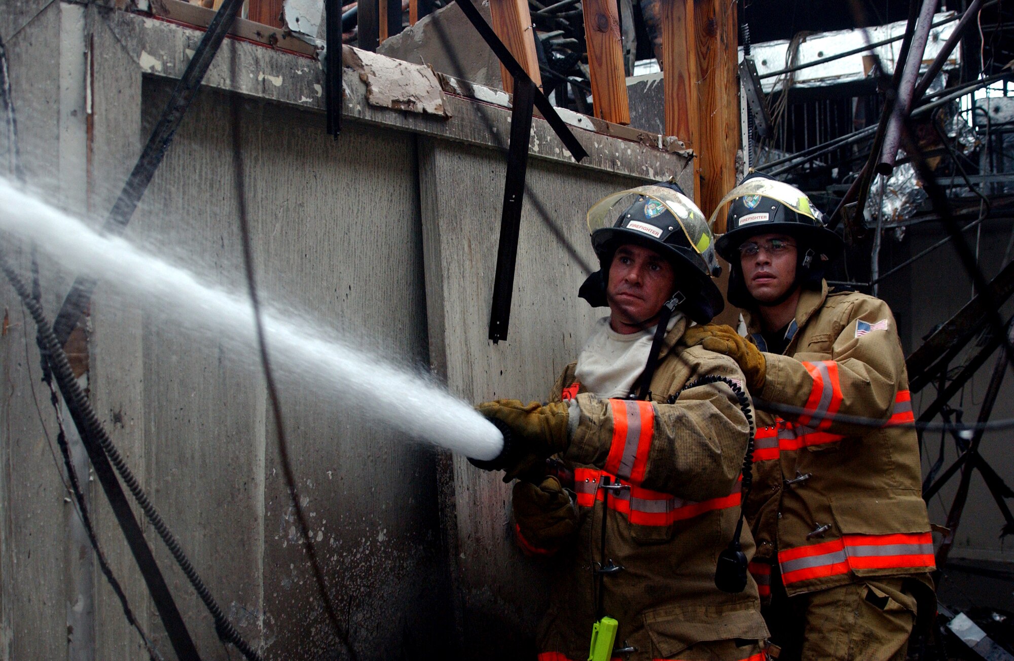 PATRICK AIR FORCE BASE, Fla. -- Base firefighters Harry Alonzo (left) and Staff Sgt. Frank Gutierrez fight a mid-morning blaze that reignited at the officers club Feb. 1.  The fire destroyed the 54-year-old building.  Although concern for the main fire had passed by daybreak, the firefighters continued to battle small flare-ups caused by the smoldering rubble and coastal breeze.  (U.S. Air Force photo by 1st Lt. Elizabeth Kreft)