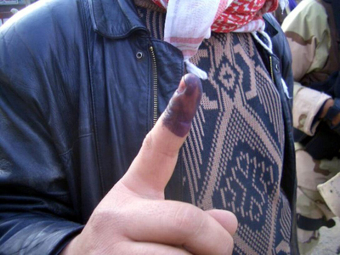 An Iraqi man proudly displays his finger stained with blue indelible ink indicating he has voted in an eastern Baghdad polling station during Iraq's first free national election in decades on Jan. 30, 2005. 