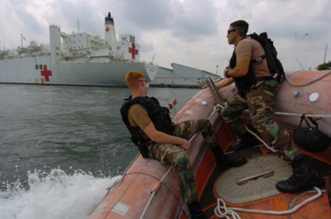 Petty Officers 2nd Class Tyler Kearsley (left) and Nathan Groom test a rigid hull inflatable boat from the USNS Mercy (T-AH 19) in Singapore's harbor on Jan. 31, 2005. Kearsley and Groom are assigned to Mobile Security Squadron 7, which is deployed aboard the Mercy en route to Indonesia to provide assistance to medical teams ashore in tsunami-affected areas. Mercy will be engaged as a support-ship, assisting medical operations ashore in support of host nation-identified humanitarian priorities. 