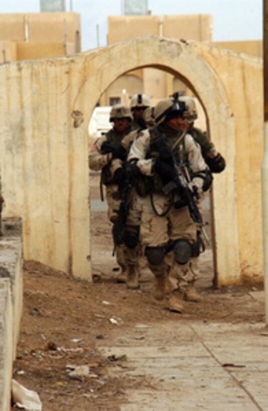 U.S. Army soldiers move towards an apartment complex as they search for weapons or bomb-making materials in the outskirts of Bayji, Iraq, on Jan. 20, 2005. The soldiers are assigned to 3rd Platoon, C Battery, 1st Battalion, 7th Field Artillery Regiment, 2nd Brigade, 1st Infantry Division. 