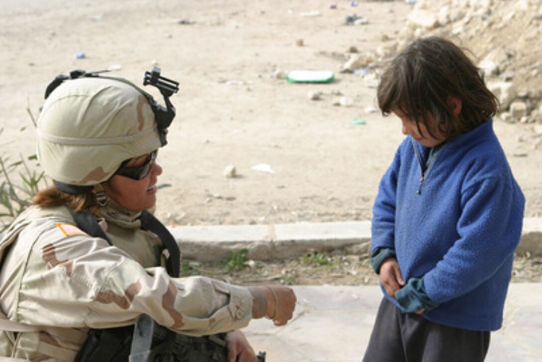 U.S. Army Sgt. Perez bends down to talk to a little Iraqi girl near the North Gate of the Cement Factory in Kharma, Iraq, on Jan. 30, 2005. Perez is assigned to the Civil Affairs Group, 1st Marine Division which is engaged in security and stabilization operations in the Al Anbar Province of Iraq. 