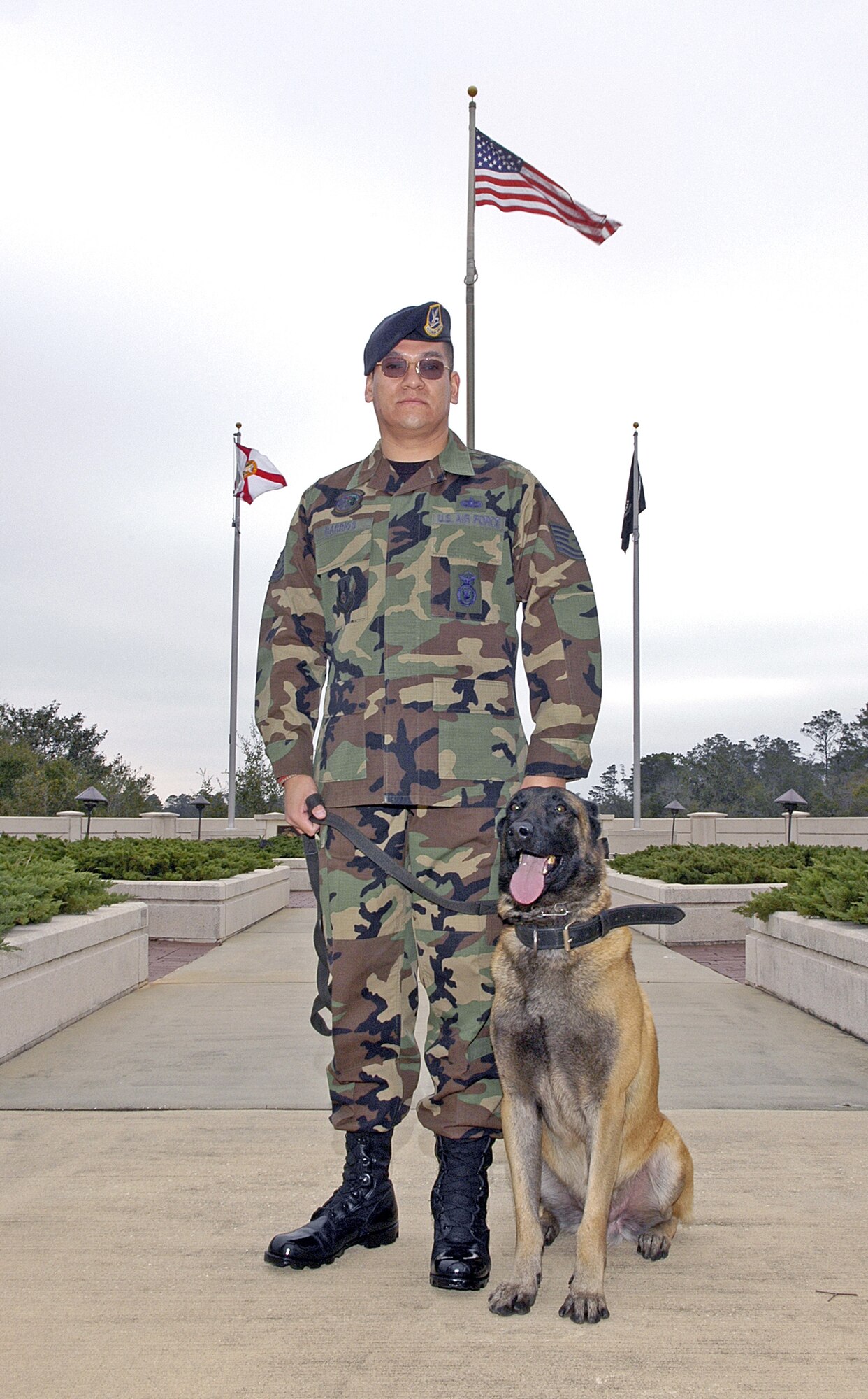 EGLIN AIR FORCE BASE, Fla. -- Tech. Sgt. Hector Barrios stands with his dog during his re-enlistment ceremony here recently.  After a two-ton concrete barrier fell on his leg and foot while deployed supporting Operation Iraqi Freedom in July 2003, Sergeant Barrios faced an 18-month struggle of amputation, reconstruction and infections before he gained medical clearance to remain in the Air Force.  Sergeant Barrios is a dog handler with the 96th Security Forces Squadron here.  (U.S. Air Force photo by Will VanderMate)