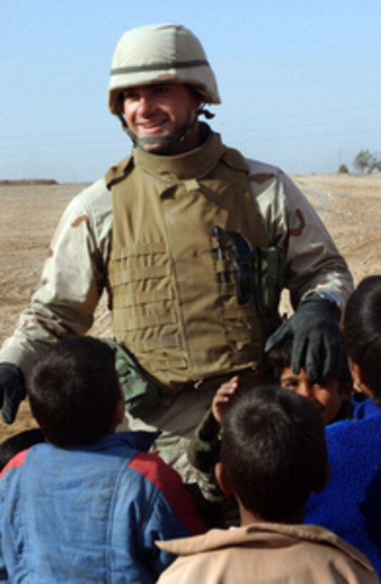 Navy Ensign Majid Awad plays with local Iraqi children in Najaf, Iraq, on Jan. 24, 2005. Awad and other Navy Seabees of Naval Mobile Construction Battalion 7 are working with residents of a small Bedouin village on the outskirts of Najaf to build a school and implement improvements to the village water, electricity, and sanitation facilities. Awad is from Bahrain. 