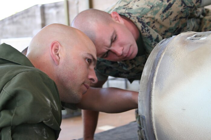 Marine Aviation Logistics Squadron 12 aviation ordnancemen Sgt. Richard Burgo (left), a native of Riverside, Calif., and Cpl. Matthew Howard, a native of Altus, Okla., inspect the assembly of a five-inch rocket at the bomb preparation area here July 18. The nine-man team of ordnancemen deployed here for Exercise Southern Frontier is building approximately 400 bombs during the exercise.