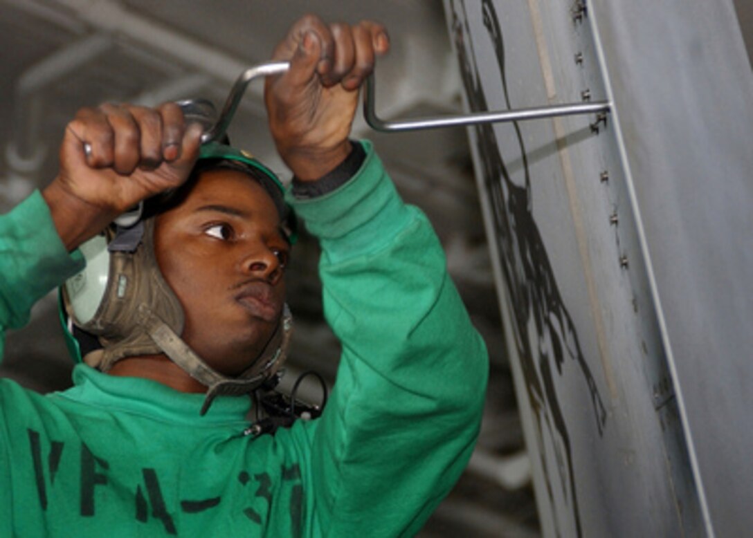Petty Officer 3rd Class Willie Brown unscrews bolts from a panel on an F/A-18C Hornet in the hangar bay of the aircraft carrier USS Harry S. Truman (CVN 75) on Jan. 31, 2005. The Truman and its embarked Carrier Air Wing 3 is providing close air support and conducting intelligence, surveillance and reconnaissance missions over Iraq while underway in the Persian Gulf. Brown is a Navy aviation electronics technician assigned to Fighter Attack Squadron 37. 